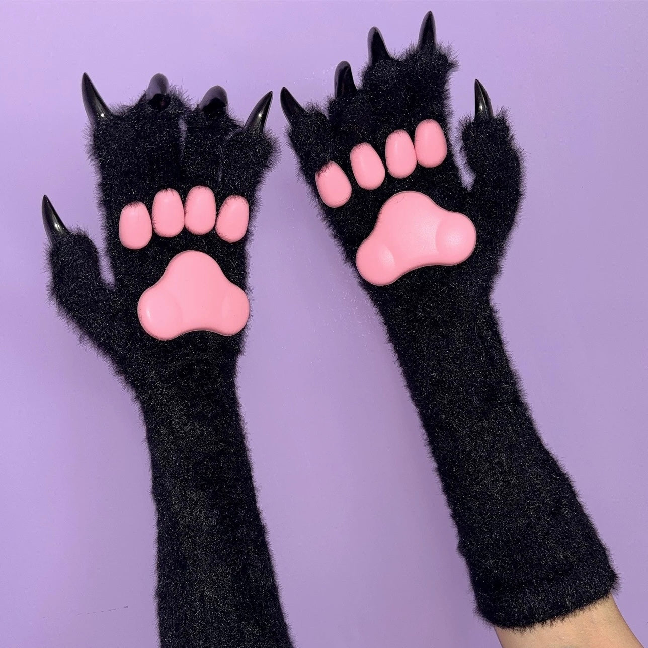 Black 3d cat paw gloves with pink pads on a purple background