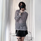 Person wearing a black and white striped shirt with a black face mask indoors.