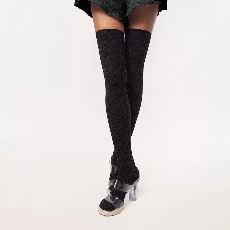 Black thigh-high socks with clear high-heeled shoes on a white background