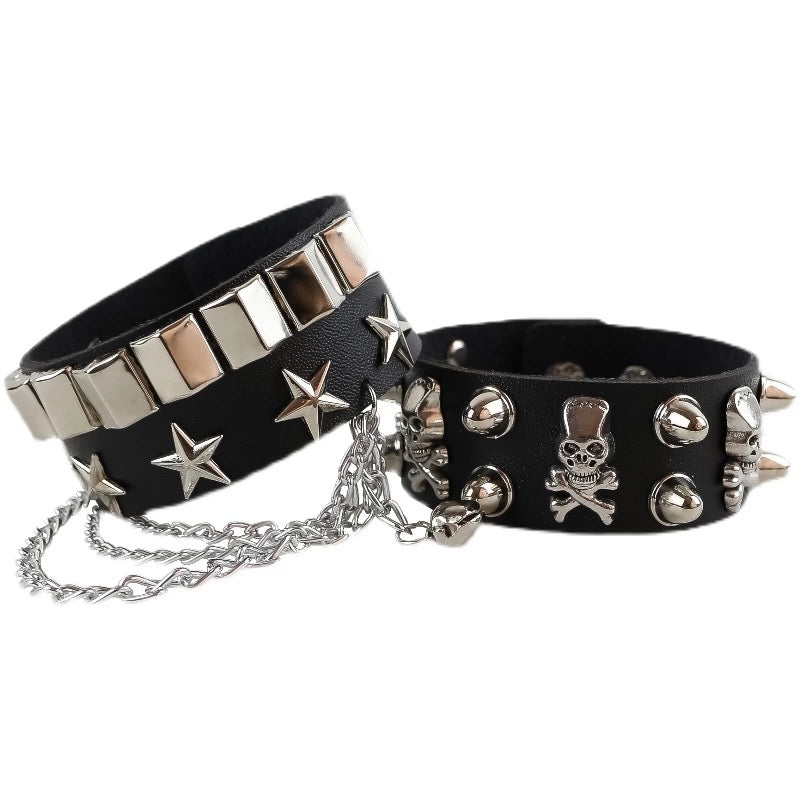 Two black gothic skull leather bracelets with metallic studs and spikes on a white background