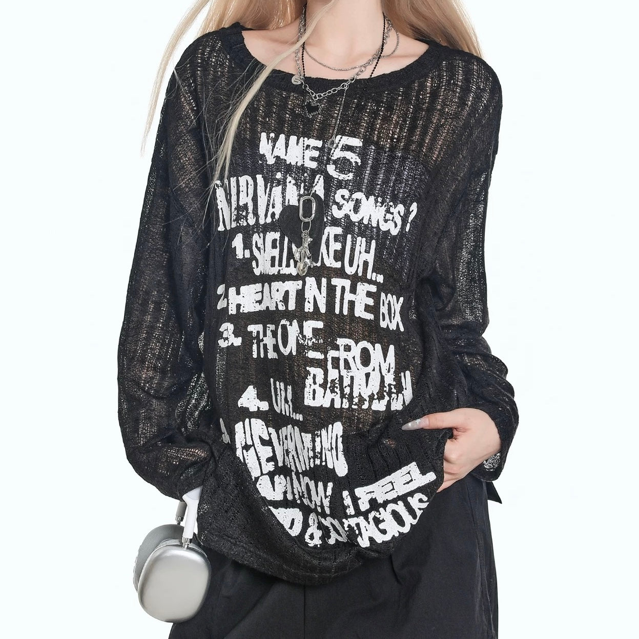 Person wearing a black outfit with sheer sleeves and a skirt against a white background