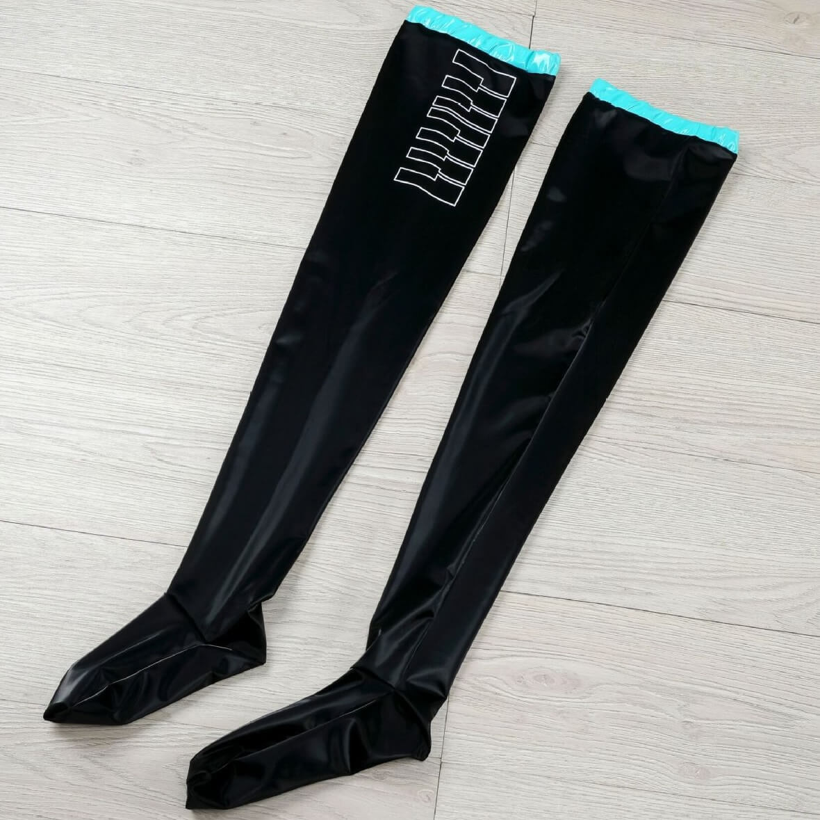 Black cosplay leather thigh highs socks with blue trim on a light wooden floor