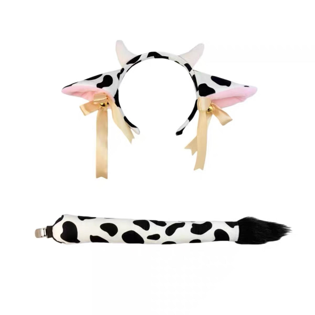 Cow-themed costume accessory set featuring a black and white spotted cow headband with pink inner ears, cream ribbons, and a matching black-and-white spotted tail clip with a black faux-fur tip, shown on a plain white background.