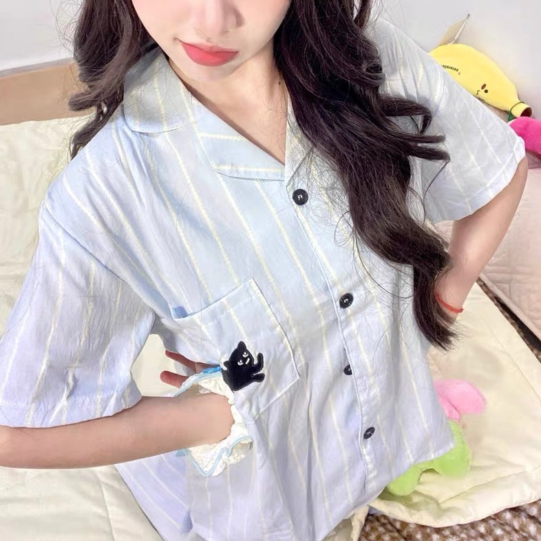 Person wearing a light blue striped shirt with black buttons, holding a small plush toy.