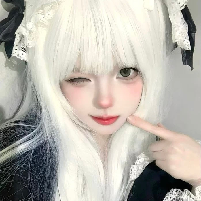 Person with long white hair and black and white outfit, pointing at camera.