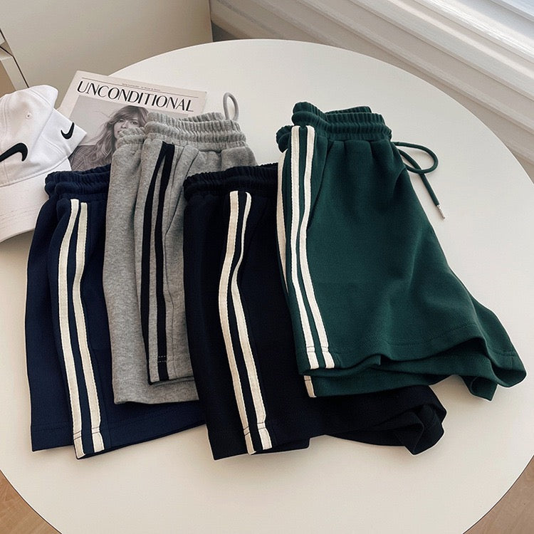 Four pairs of jogger pants in different colors on a round white table.