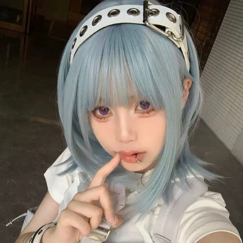 Person with light blue hair and a white headband posing indoors.