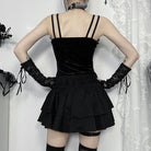 Person wearing a black gothic zip-up corset top with thin straps and a tiered skirt, standing against a white curtain.