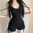 Person wearing a black romper with a plain background