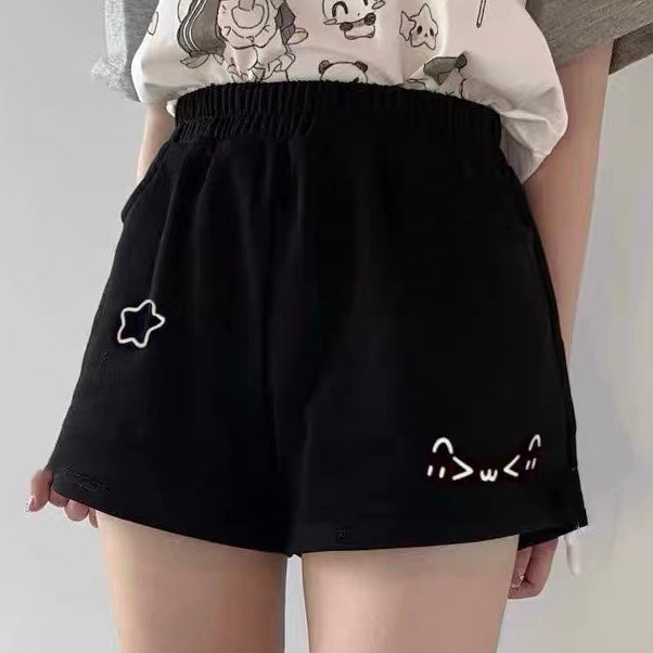 Black shorts with white cat designs worn by a femboy a plain background