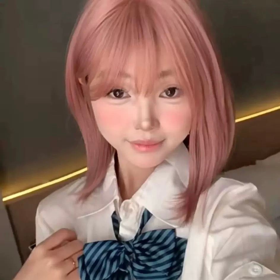 Person with pink hair wearing a white shirt and blue bow tie in an indoor setting