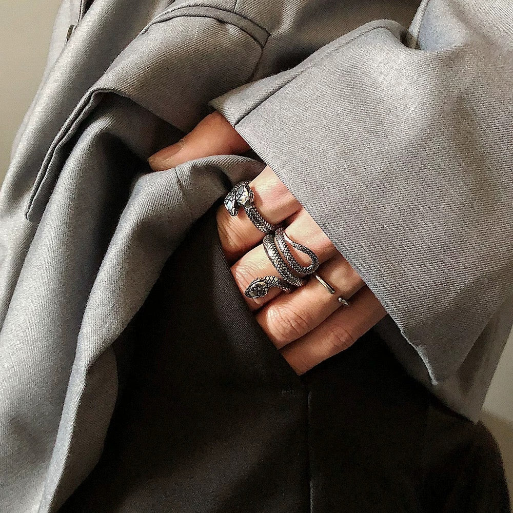 Close-up of a hand wearing multiple rings with a gray coat in the background