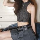 Person wearing a black patterned crop top and gray skirt sitting on a blue couch.