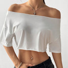 White off-shoulder top worn by a person on a plain background