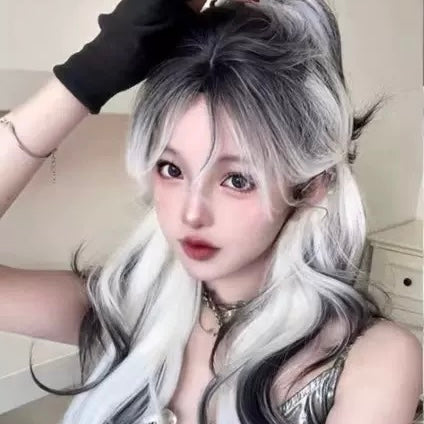 Person with styled hair and makeup, wearing a black top indoors.