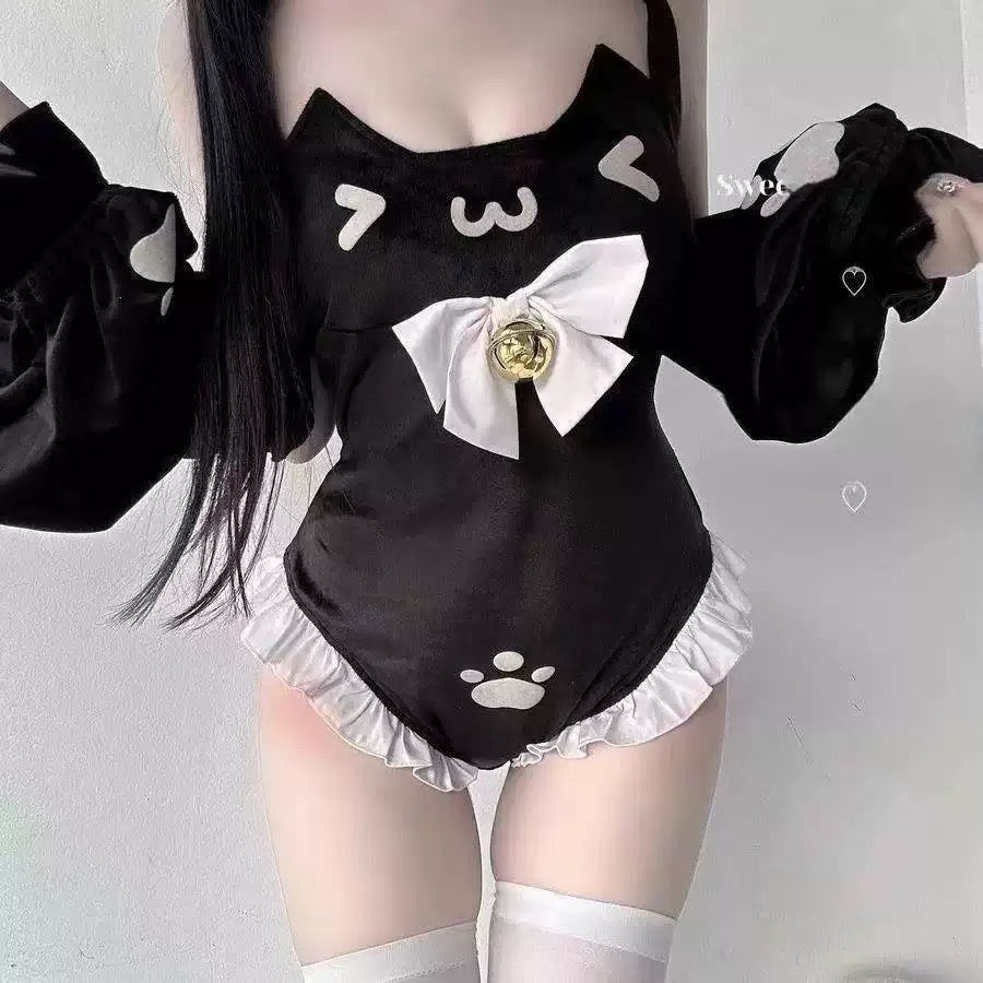 A femboy wearing a black cat-themed maid swimsuit with white ruffles, a white bow with a gold center, and white thigh-high socks against a plain light gray wall.