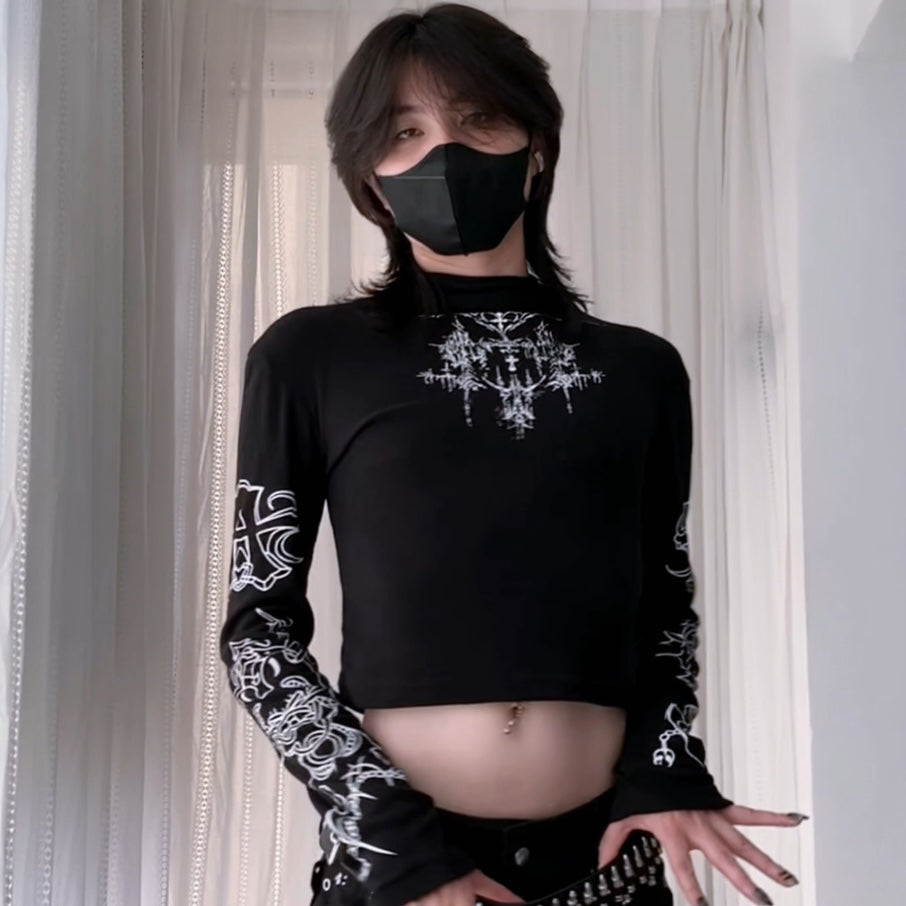 Person wearing a black cropped sweatshirt with a sun design and a black skirt, standing against a white curtain.