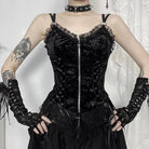 Person wearing a black gothic zip-up corset top with matching gloves against a white curtain background