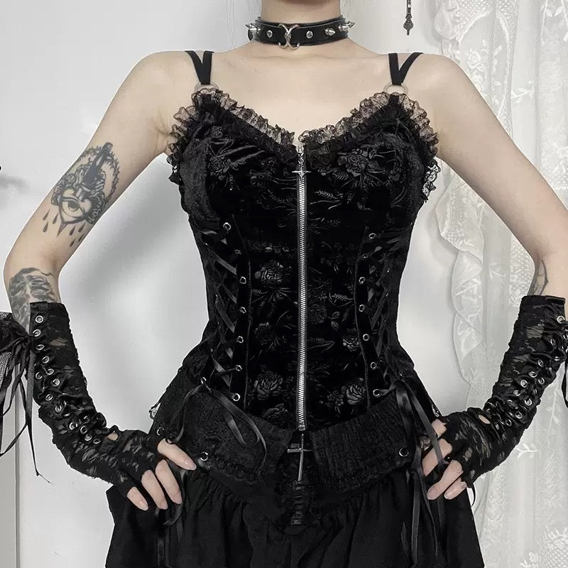 Person wearing a black gothic zip-up corset top with matching gloves against a white curtain background