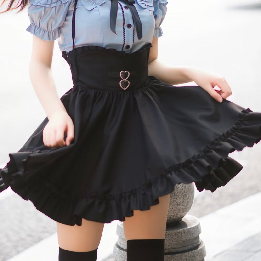 Person wearing a black skirt with heart-shaped buttons and a light blue top.