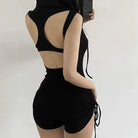 Person wearing a black swimsuit with cut-out design on a plain background