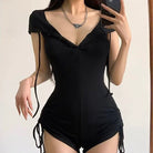Person wearing a black romper with a plain background