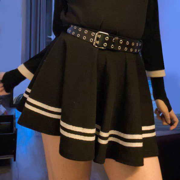 Person wearing a black skirt with white stripes and a belt
