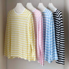 Four striped long-sleeve shirts in yellow, pink, blue, and black and white on mannequins against a neutral background.