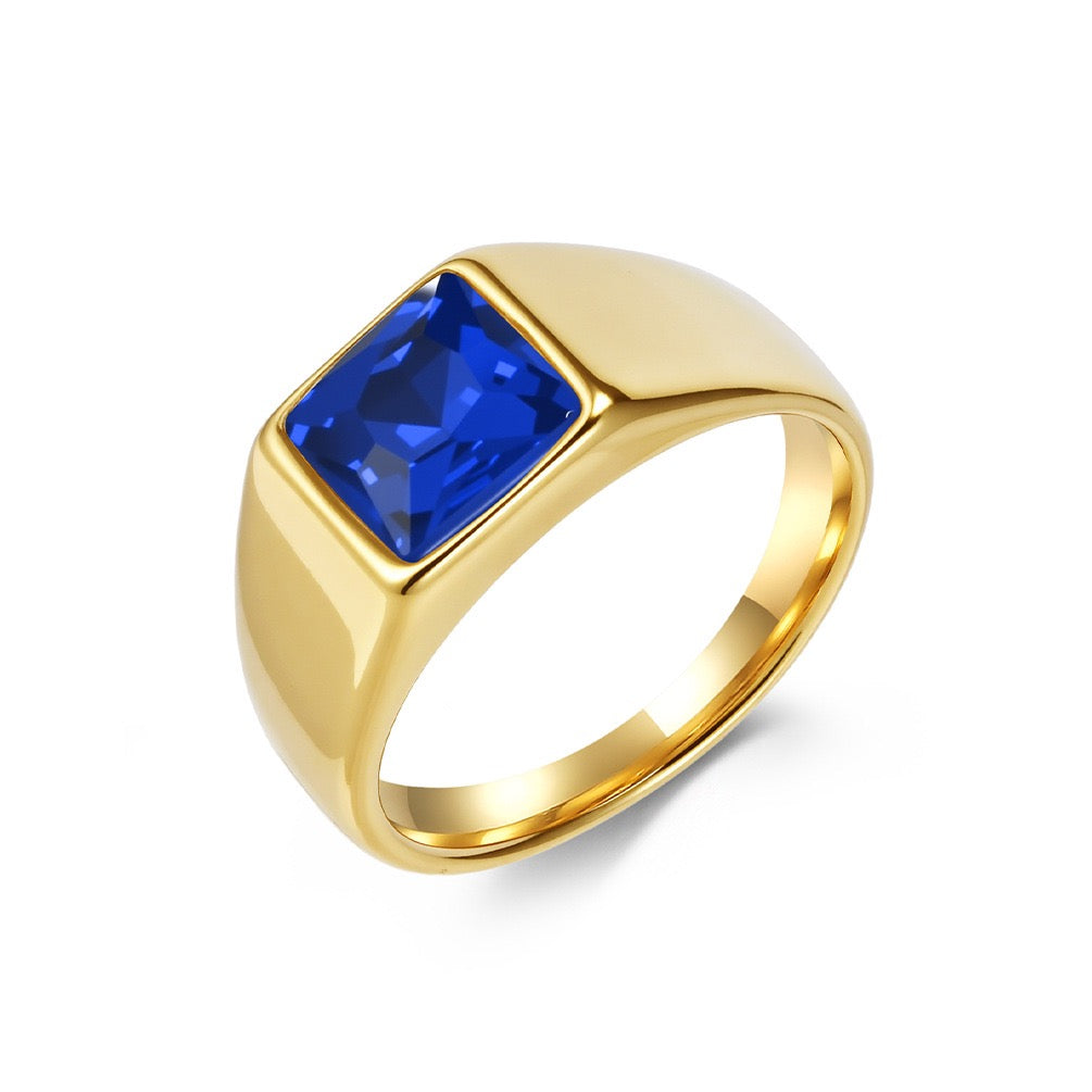 Gold ring with a blue gemstone on a white background