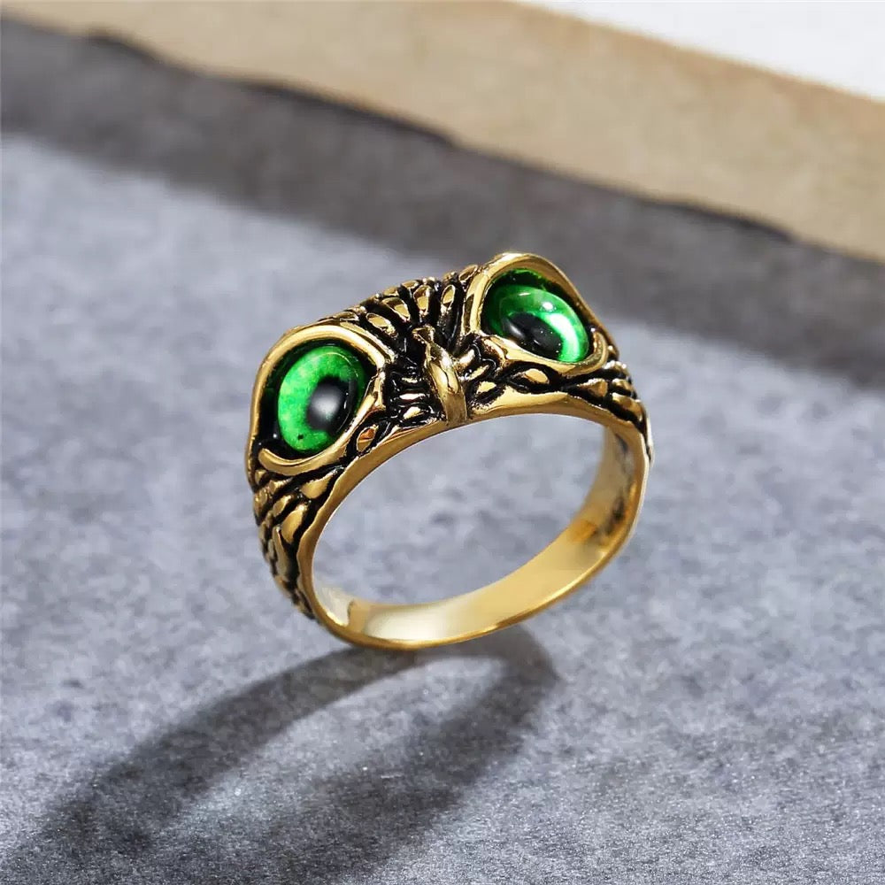 Gold ring with green gemstones on a gray surface