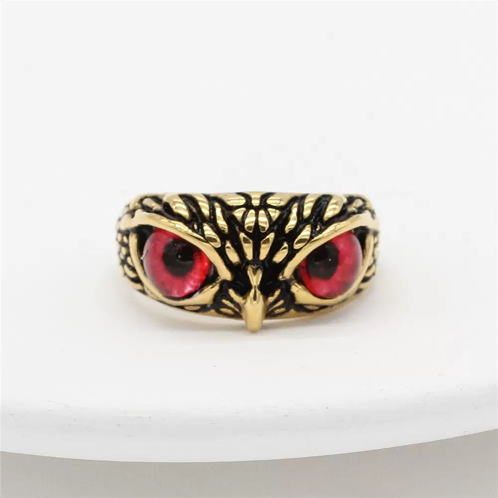 Gold owl ring with red eyes on a white background
