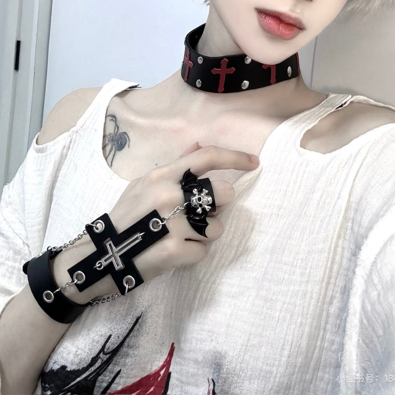 Person wearing a black gothic cross skull ring chain bracelet