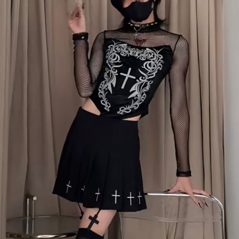 Person wearing a black outfit with white designs, standing against a beige curtain.