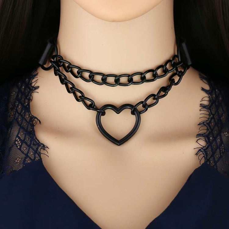 Black chain choker with heart design on a mannequin neck against a dark background