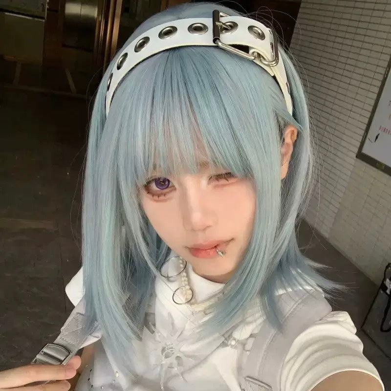 Person with light blue hair wearing a white outfit in an indoor setting