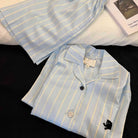 Light blue and yellow striped shirt with a black bear logo on a dark surface