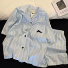 Light blue striped shirt and shorts oajama set with black buttons on a white background