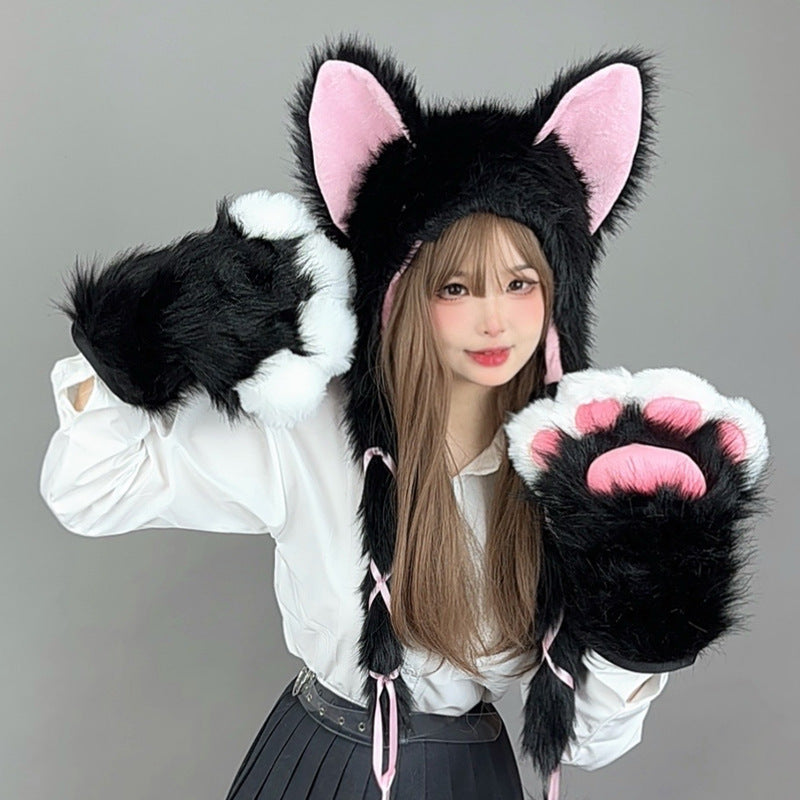 Person wearing a black and pink cat-themed hat and gloves on a gray background