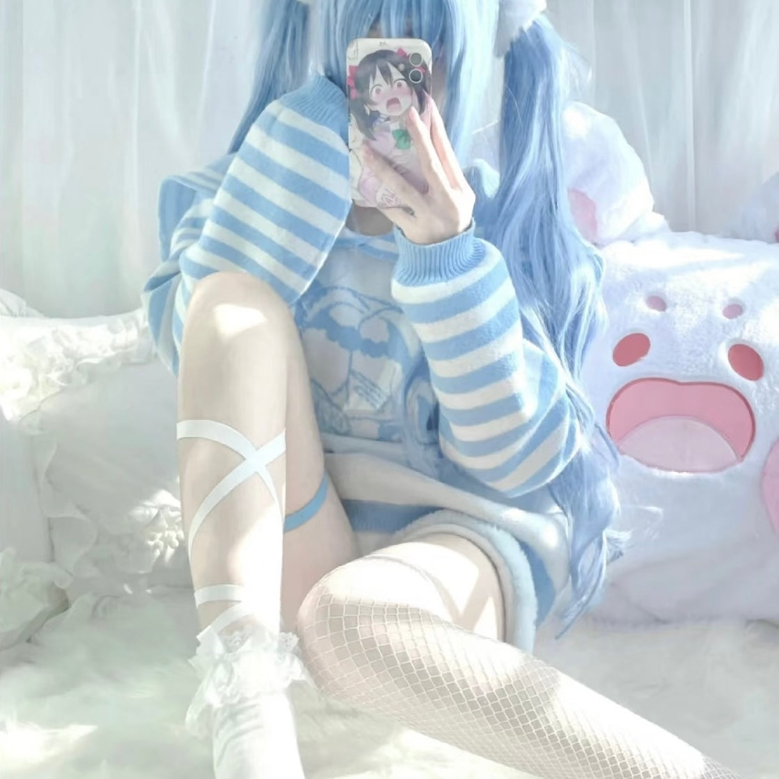 Person wearing a blue and white striped outfit with long hair, sitting on a bed.