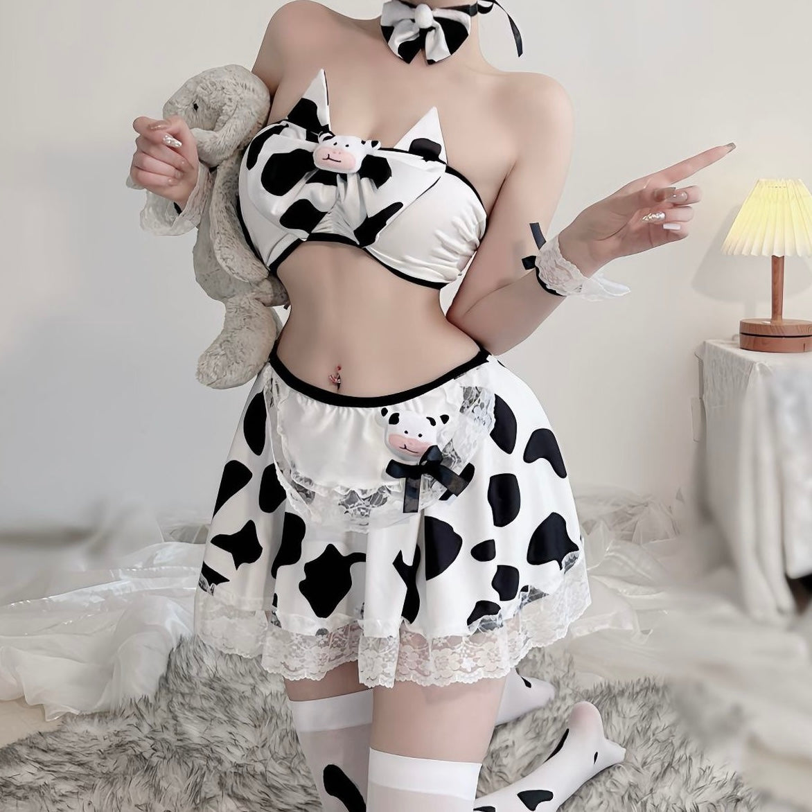 Person wearing a cow print outfit with a skirt and top, holding a plush toy.