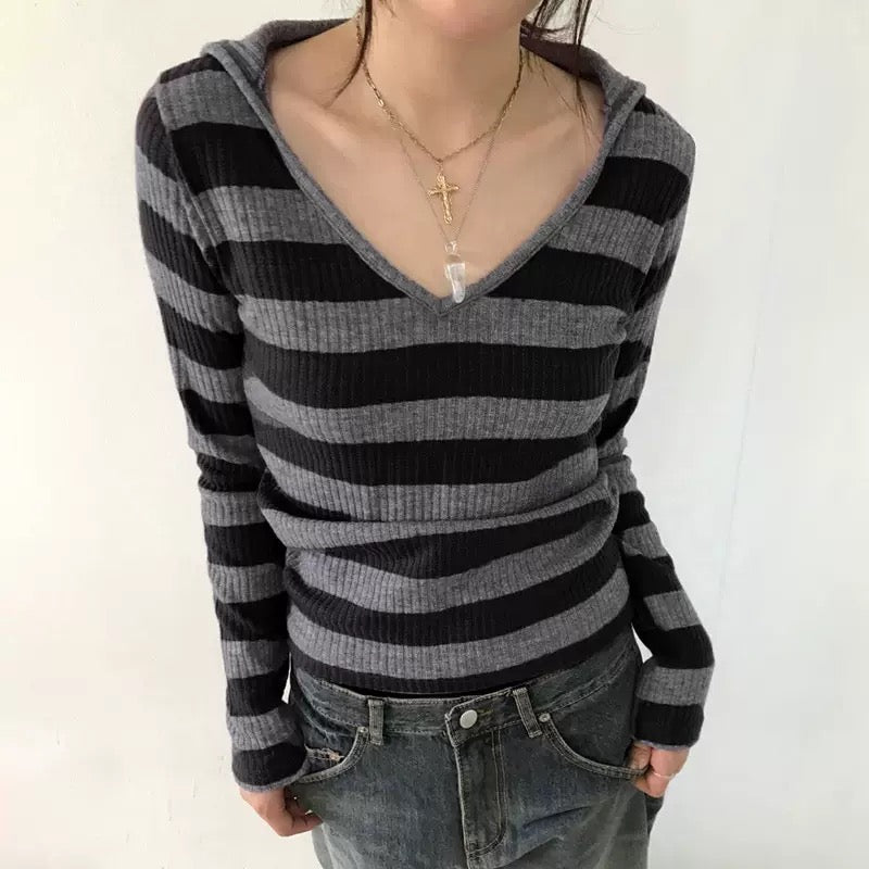Person wearing a black and gray striped hoodie with a plain background