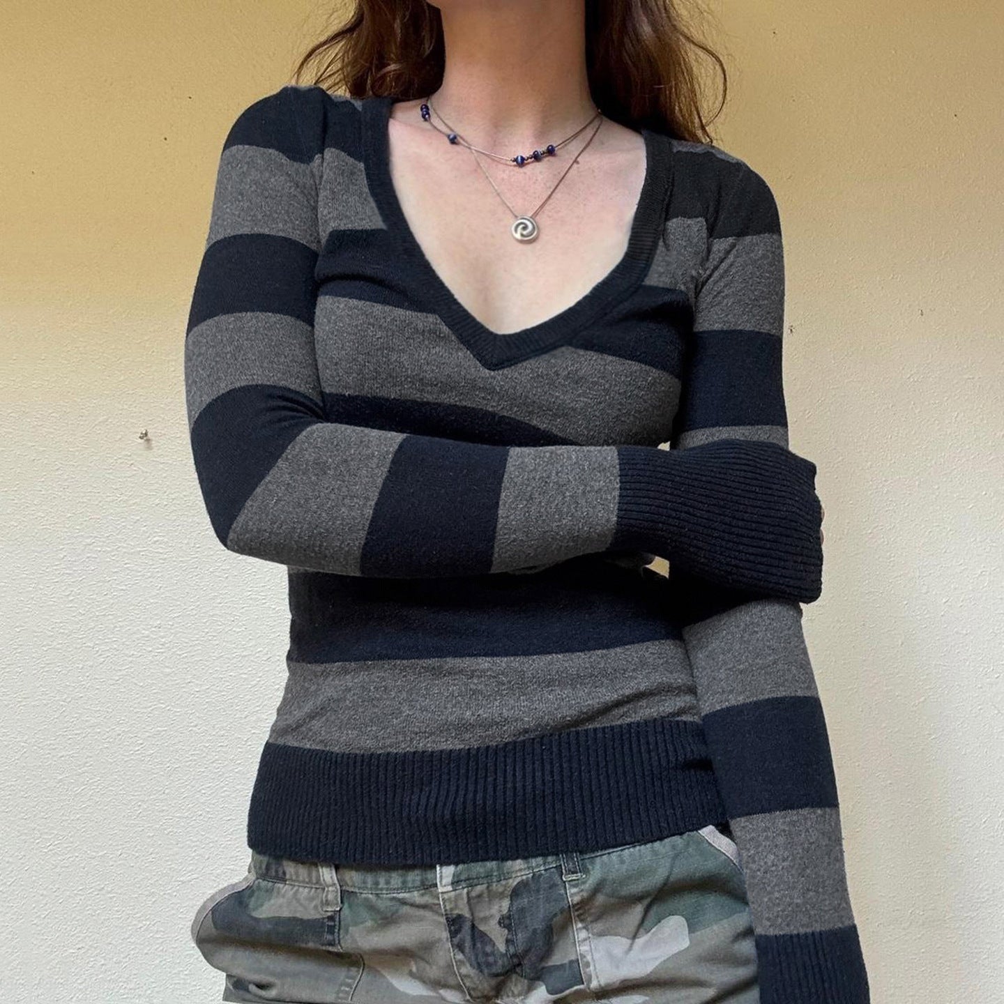Person wearing a black and gray striped hoodie with a plain background