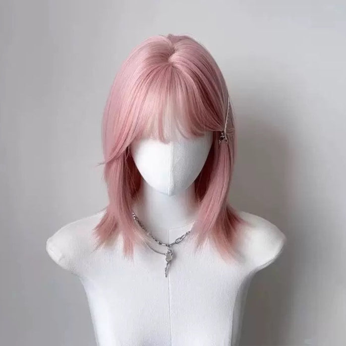 Pink wig on a mannequin head against a plain background