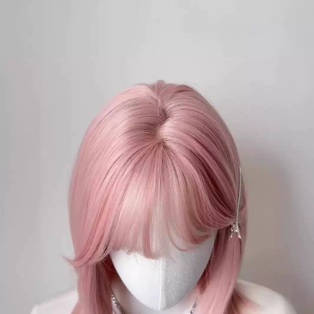 Pink wig on a mannequin head against a plain background
