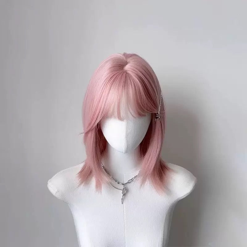 Pink wig on a mannequin head against a plain background