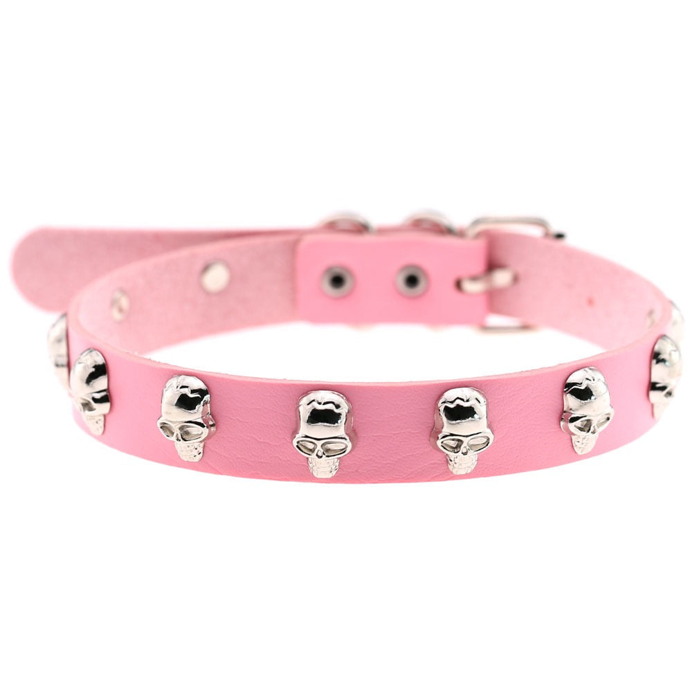 A pink leather collar decorated with multiple silver skull studs, shown against a plain white background.