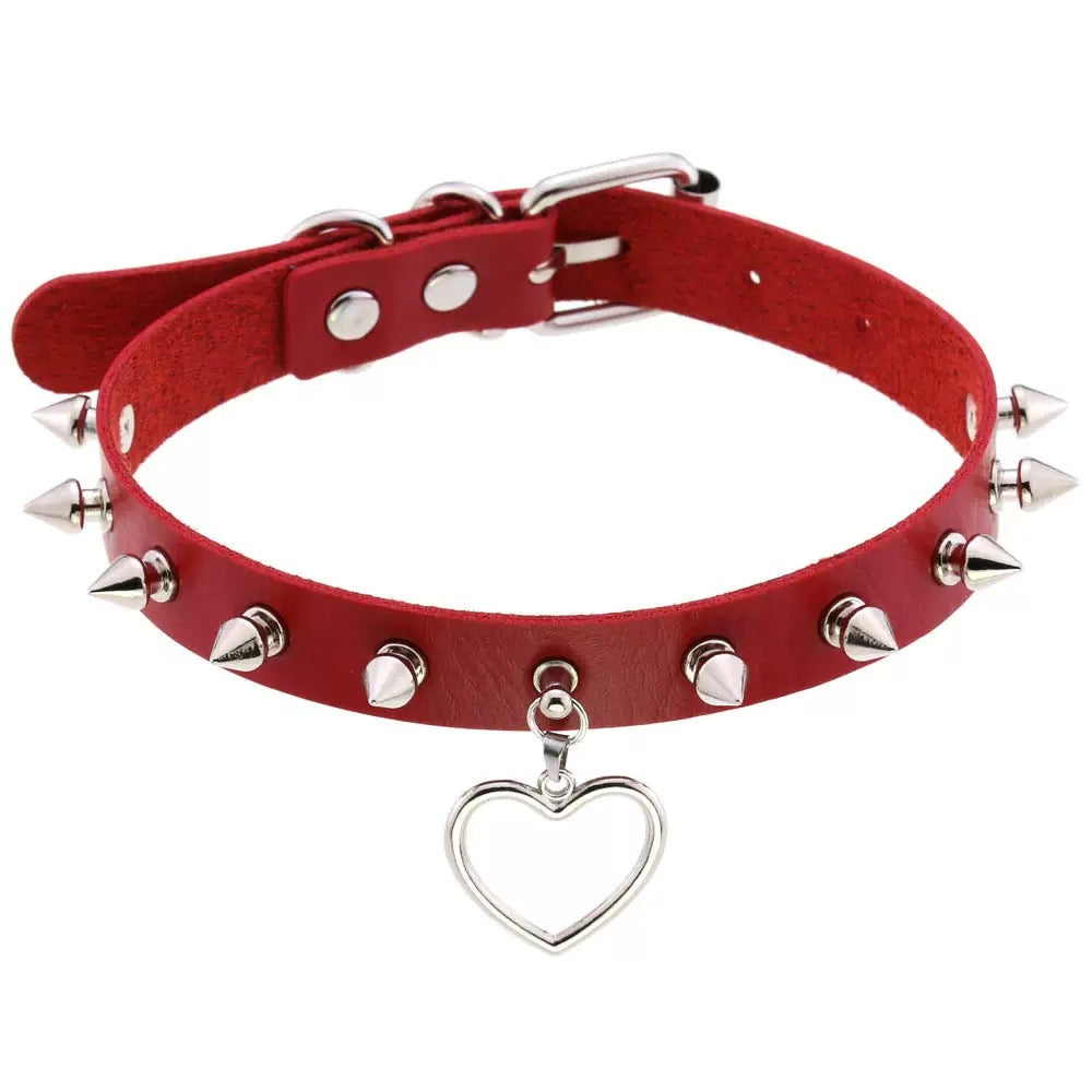 Red leather choker with silver spikes and a heart-shaped charm on a white background