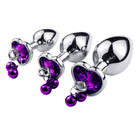 Metallic anal plugs with purple heart-shaped crystals on a white background