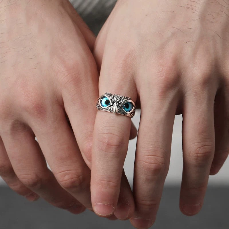 Close-up of a hand wearing an owl-shaped ring with blue gemstones.
