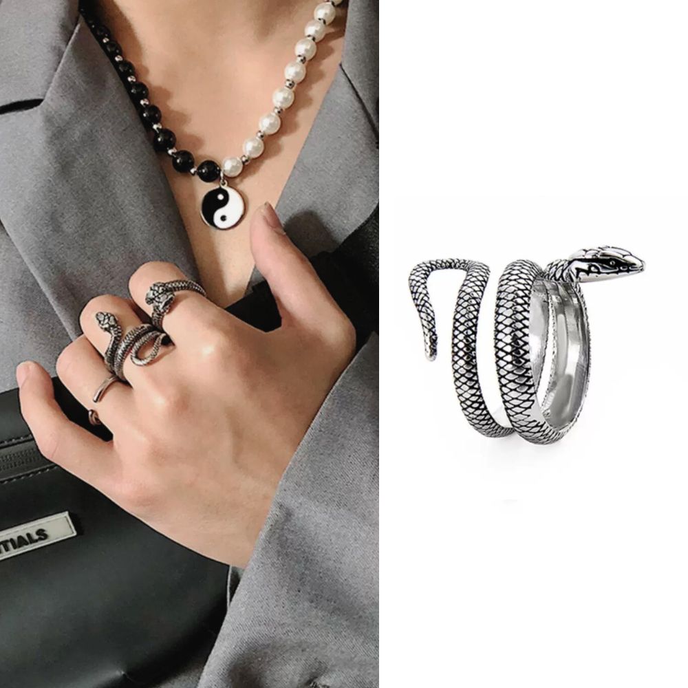 Silver snake-shaped rings on a hand with a necklace, displayed against a white background.